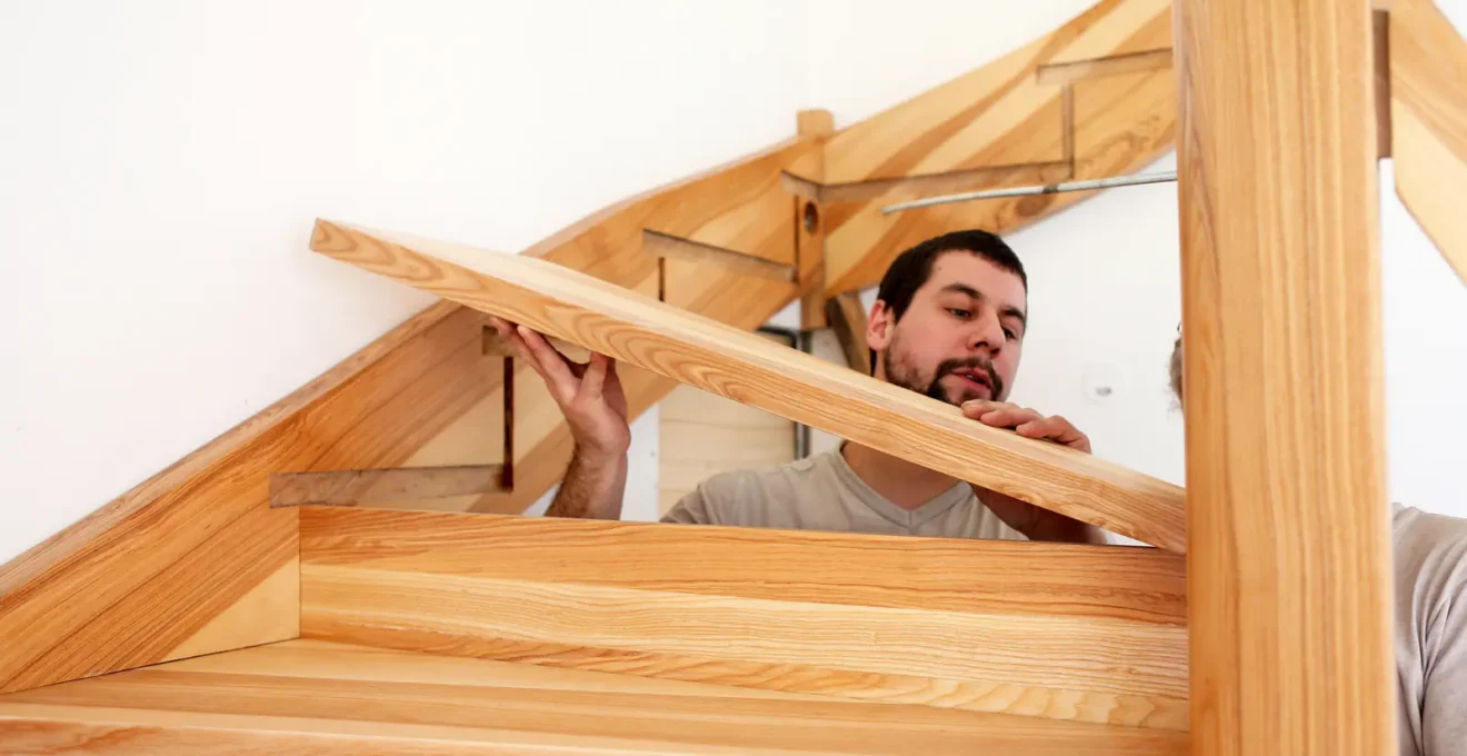 Entrepreneur certifié RBQ prenant des mesures sur un escalier lors d'une consultation de rénovation résidentielle au Québec.